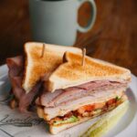 Club sandwich on toasted bread with a pickle and a mug of coffee