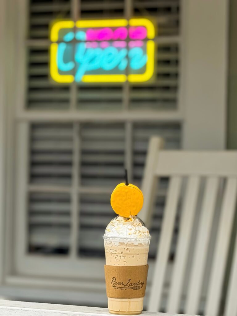 Frappe held up under a neon Open sign