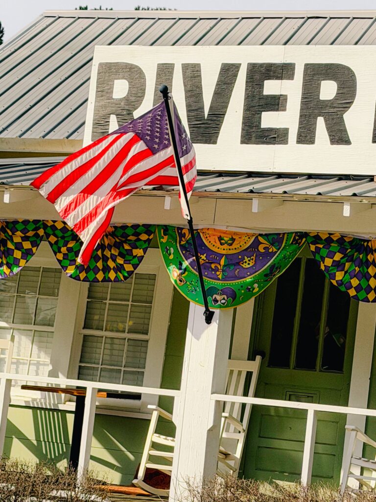Front porch of River Landing Coffee Co. in McIntosh with a flag and Mardi Gras decorations