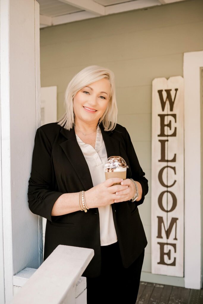 Owner Shannon Turner holding a coffee on the front porch of River Landing Coffee